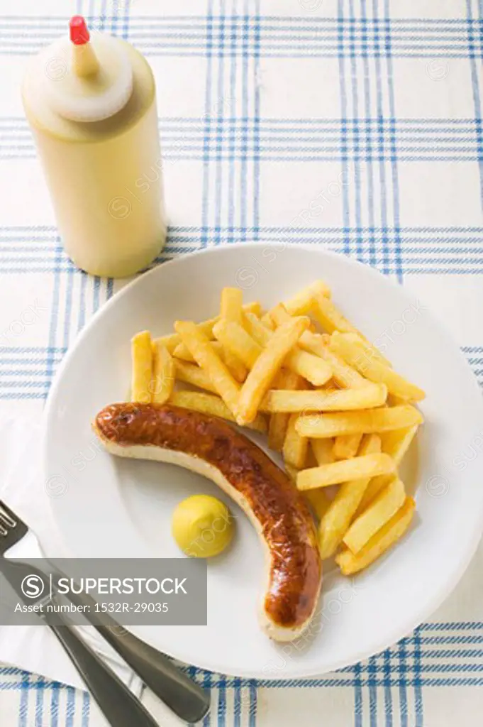 Sausage with chips and mustard on plate in restaurant
