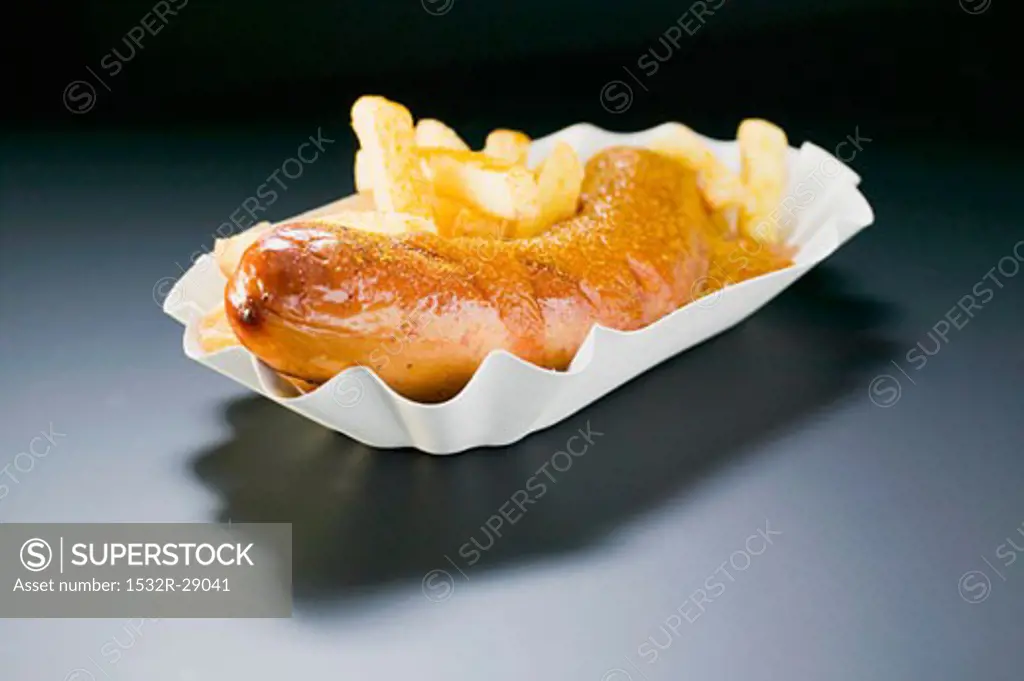 Currywurst (sausage with ketchup & curry powder) & chips on paper dish