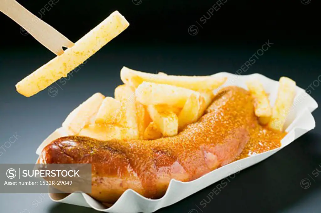 Sausage with ketchup & curry powder & chips, one on wooden fork