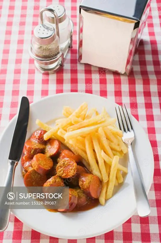 Currywurst (sausage with ketchup & curry powder) & chips in restaurant
