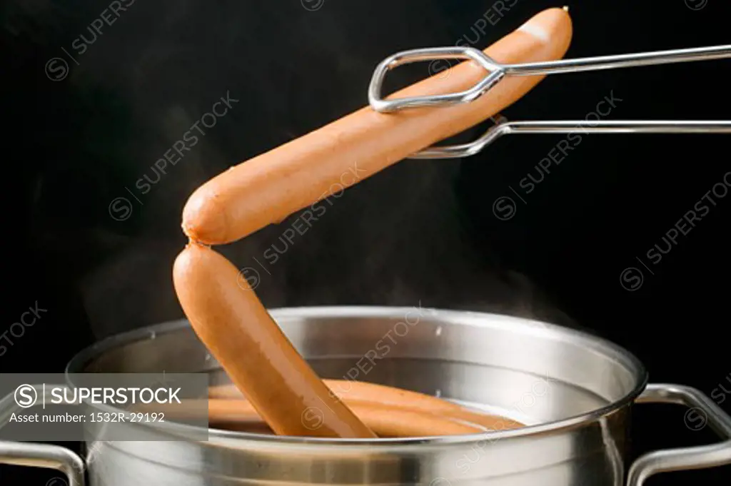 Lifting frankfurters out of hot water with tongs