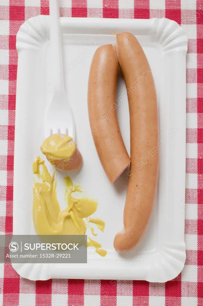Frankfurters with mustard on paper plate