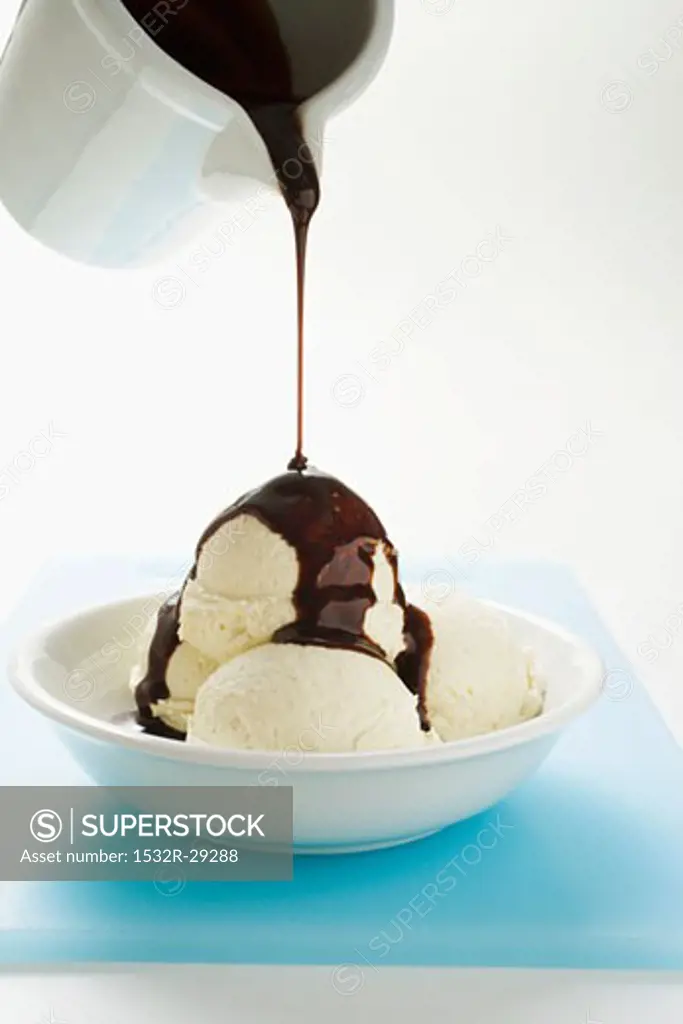 Pouring chocolate sauce over vanilla ice cream