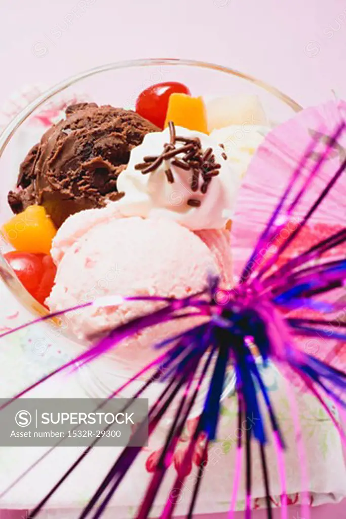 Mixed ice cream with fruit, cream and cocktail umbrella