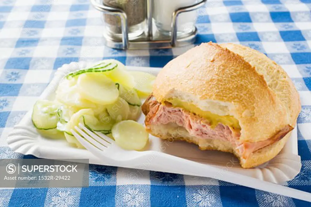 Leberkäse in roll with mustard & potato salad on paper plate