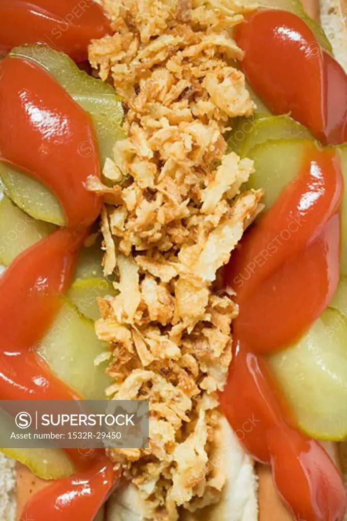 Hot dogs with ketchup, gherkins & fried onions (close-up)