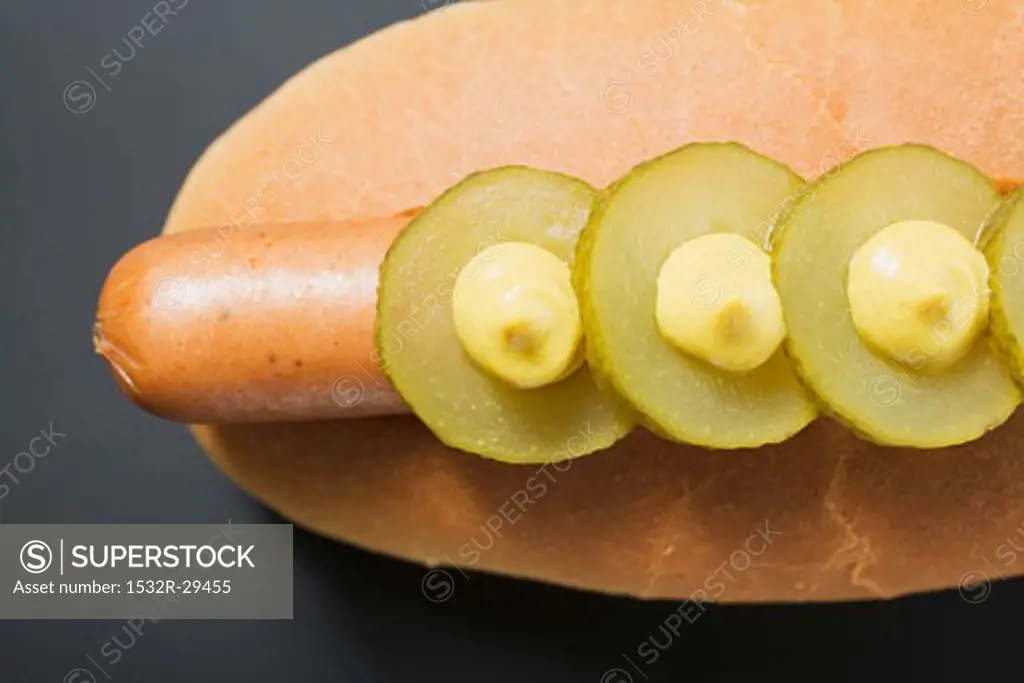 Hot dog with gherkins and mustard (overhead view)