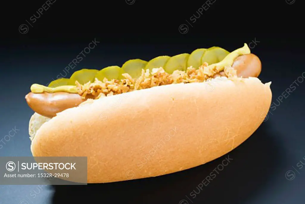 Hot dog with gherkins, fried onions and mustard