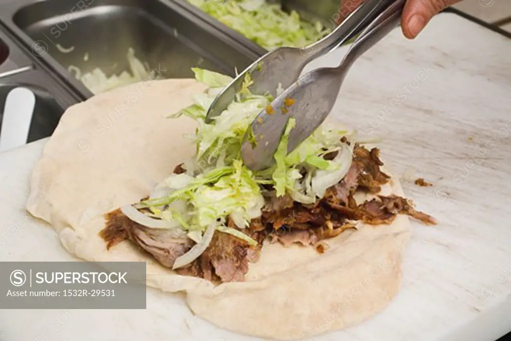 Making a döner wrap (topping with lettuce)