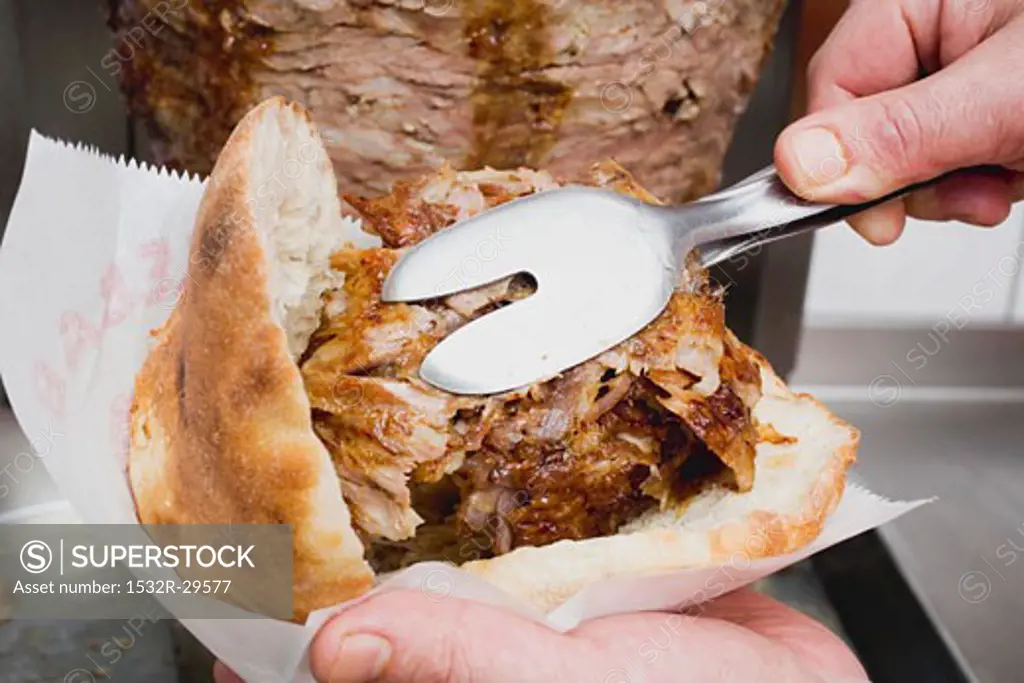 Making a döner kebab: filling pita bread with meat
