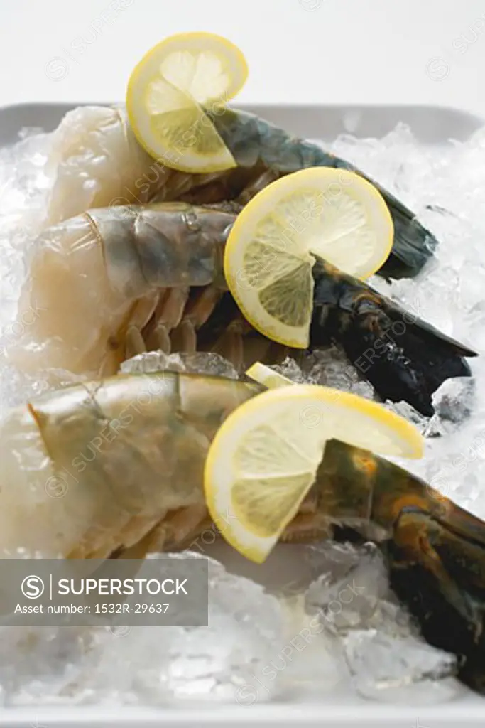Fresh king prawns with lemon slices on ice