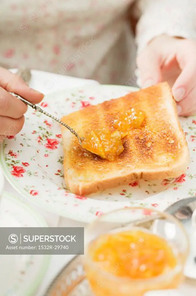Spreading orange marmalade on toast