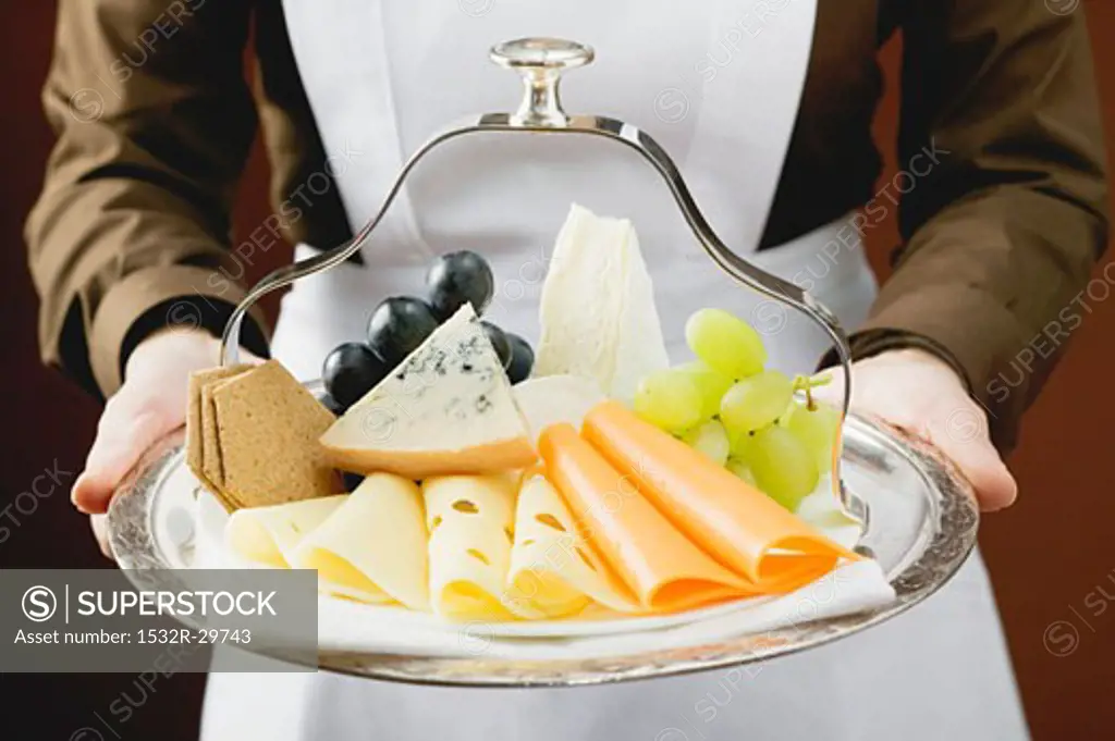 Waitress serving a cheese platter with grapes and crackers