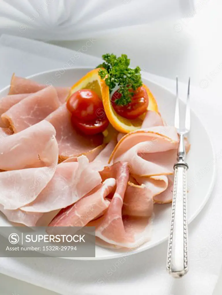 Platter of ham with cherry tomatoes, orange and parsley