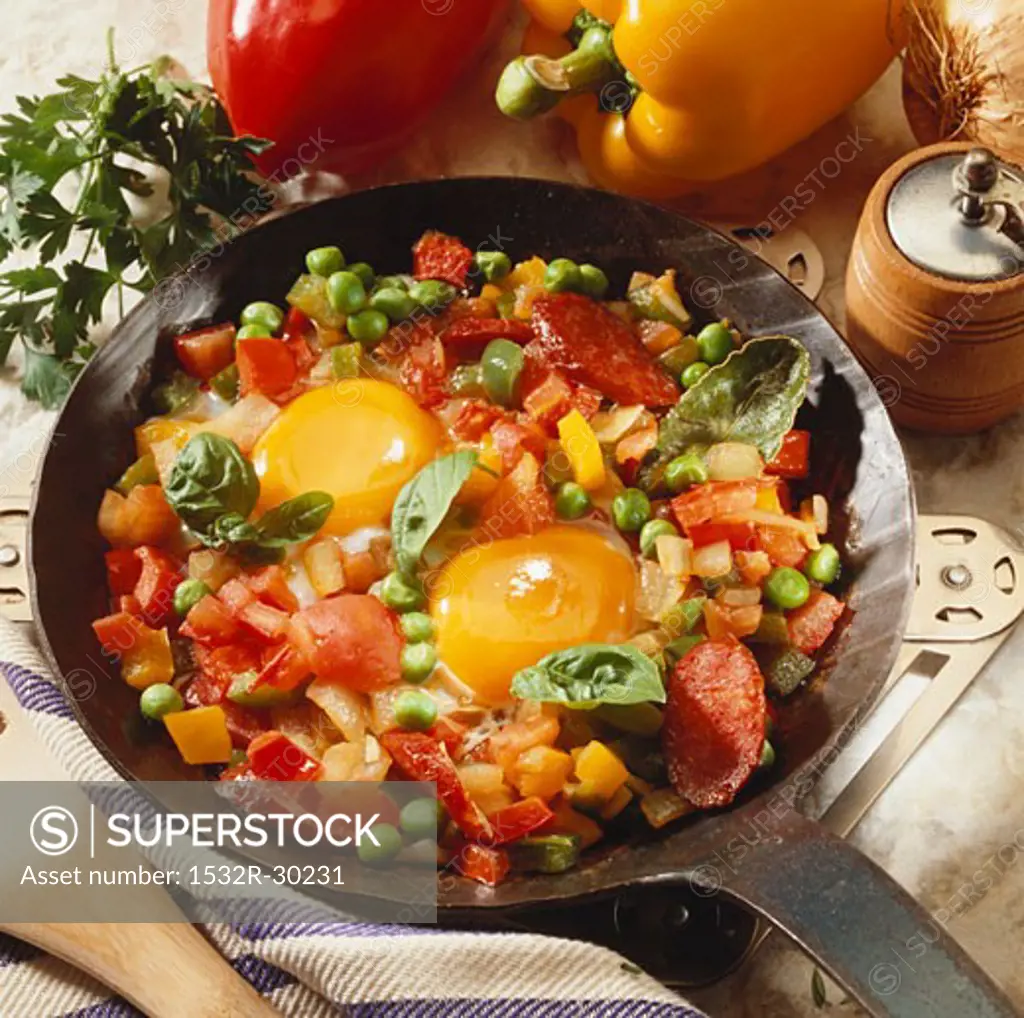Fried eggs, vegetables and sausage in frying pan