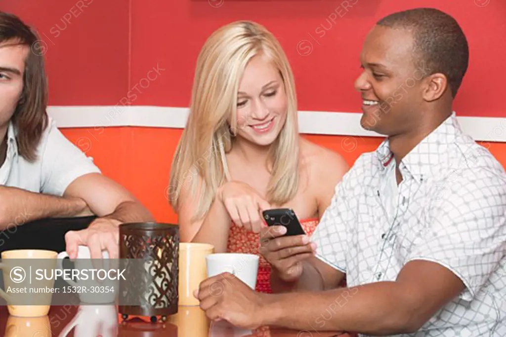 Young people with mobile phone at table in a café or restaurant