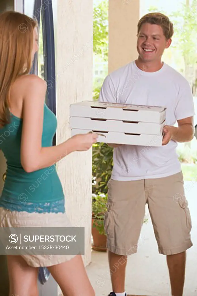 Young woman at house door receiving pizza delivery