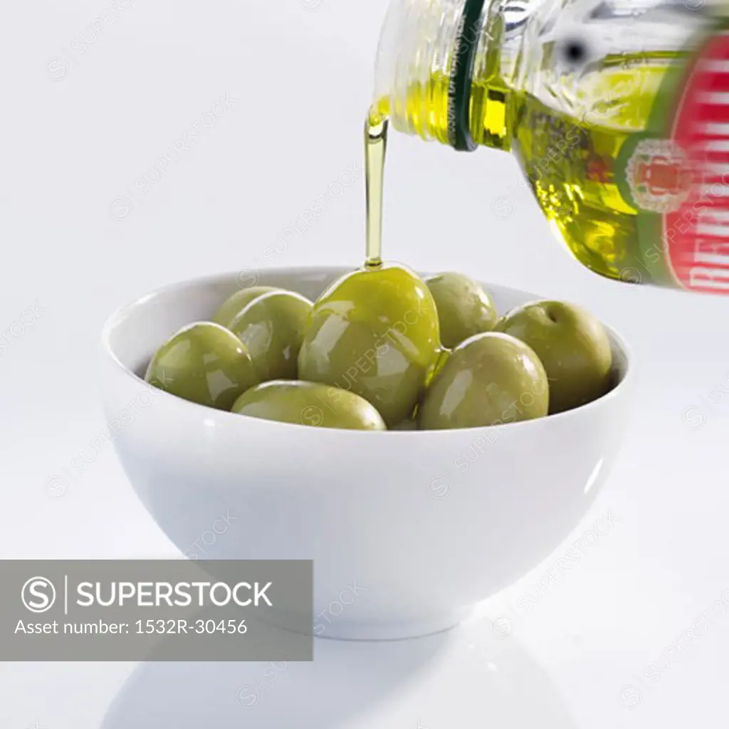 Pouring olive oil over olives