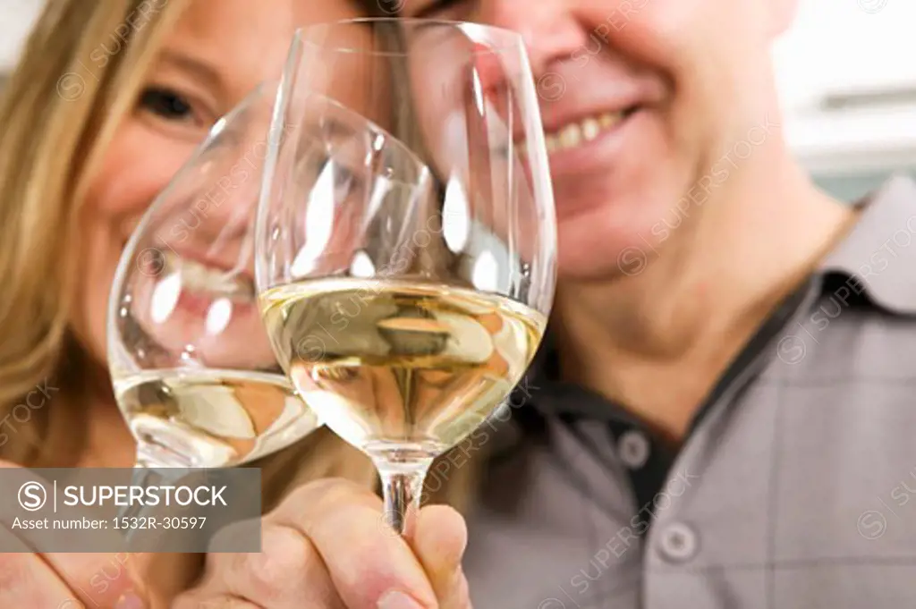 Man and woman clinking glasses of white wine together
