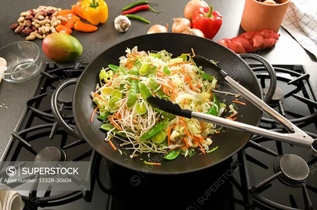 Vegetables in wok on hob, Asian ingredients behind