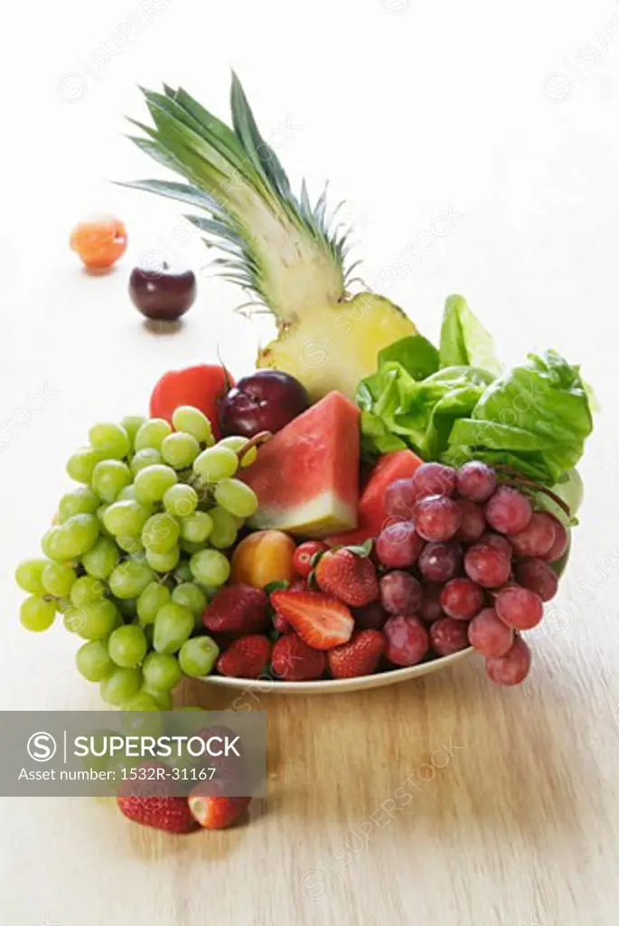 Plate of fruit: grapes, melon, pineapple, strawberries etc.