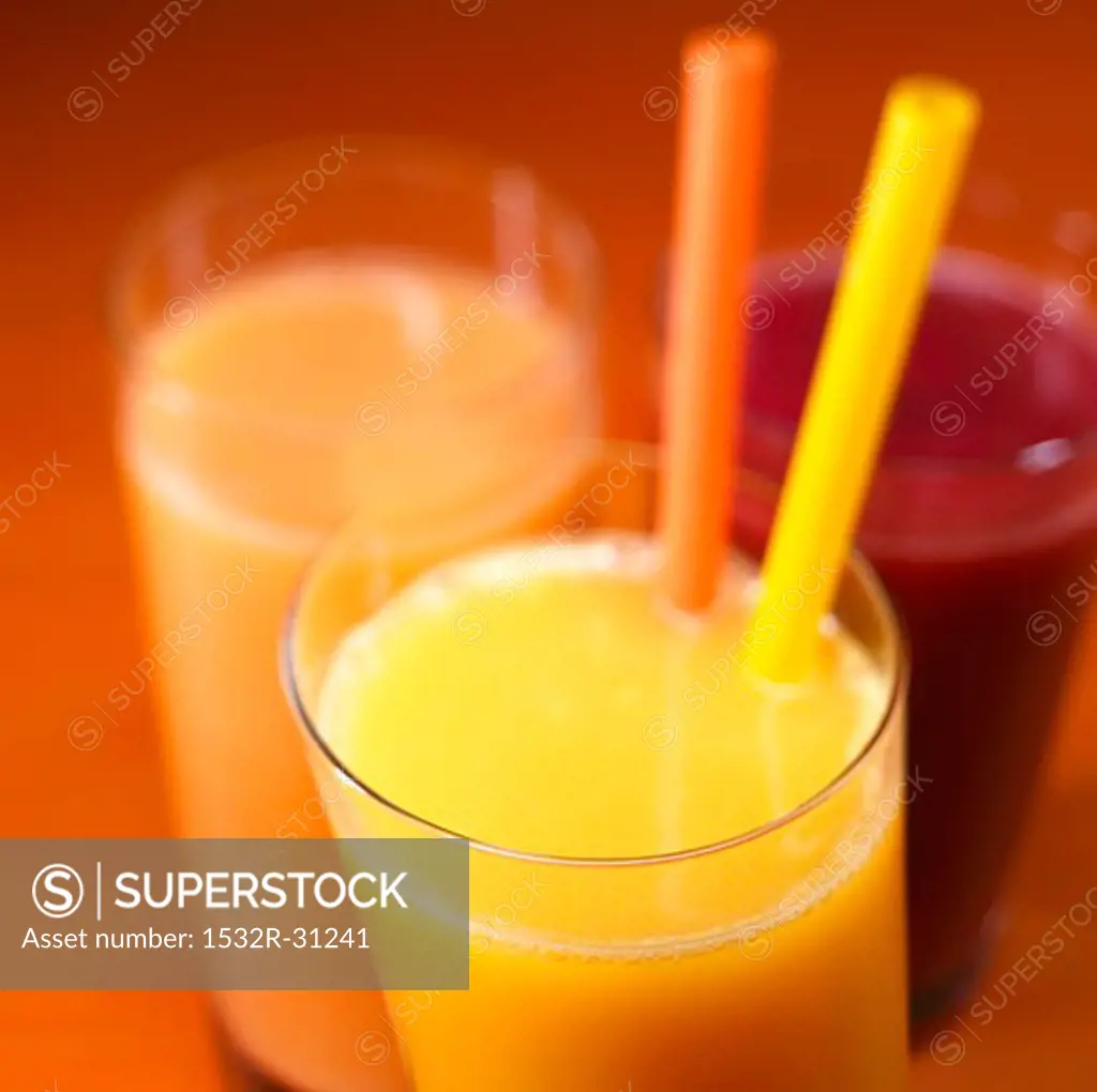 Orange juice with two straws, grapefruit juice & cherry juice