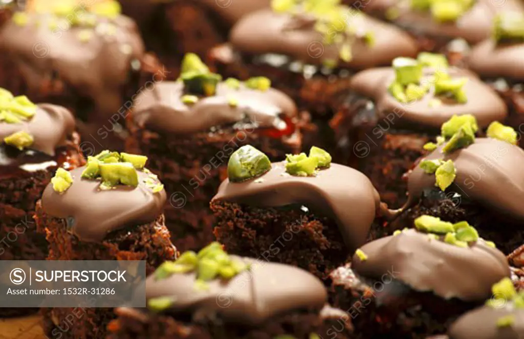 Brownies with redcurrant jelly, chocolate icing & pistachios