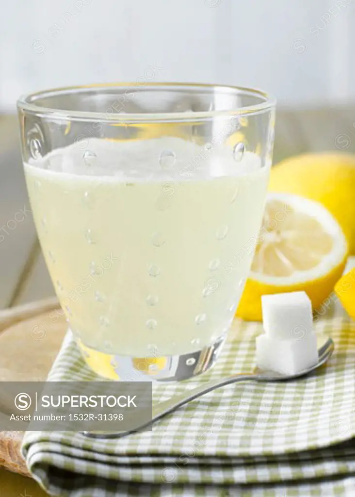 Hot lemon with sugar cubes, lemons in background