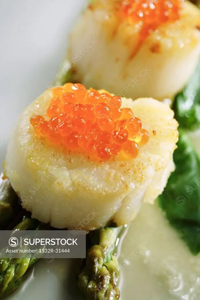 Scallops with salmon caviar on asparagus
