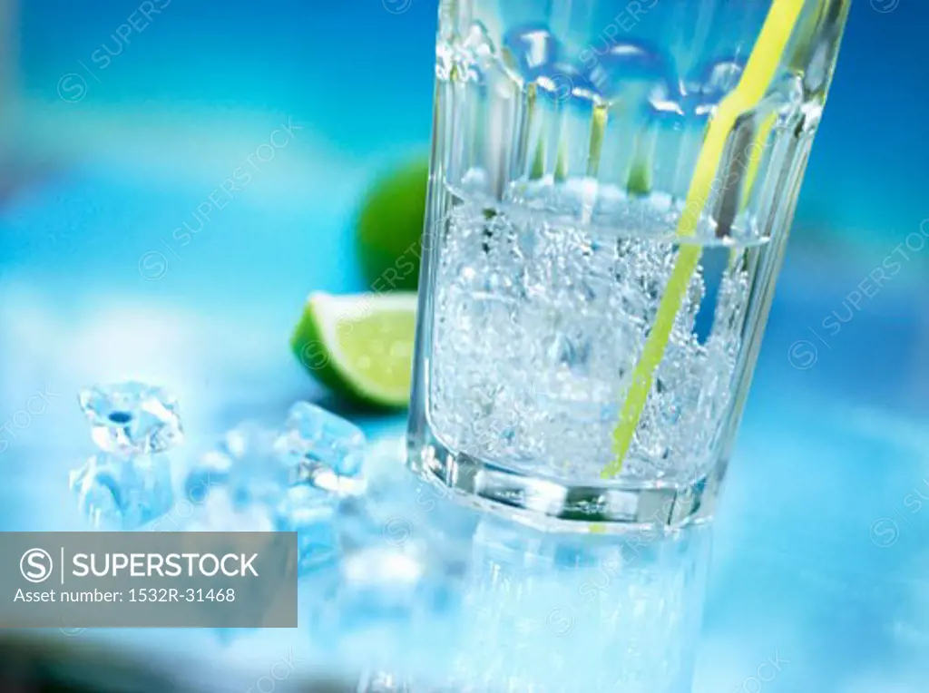 A glass of mineral water with straw, crushed ice and lime