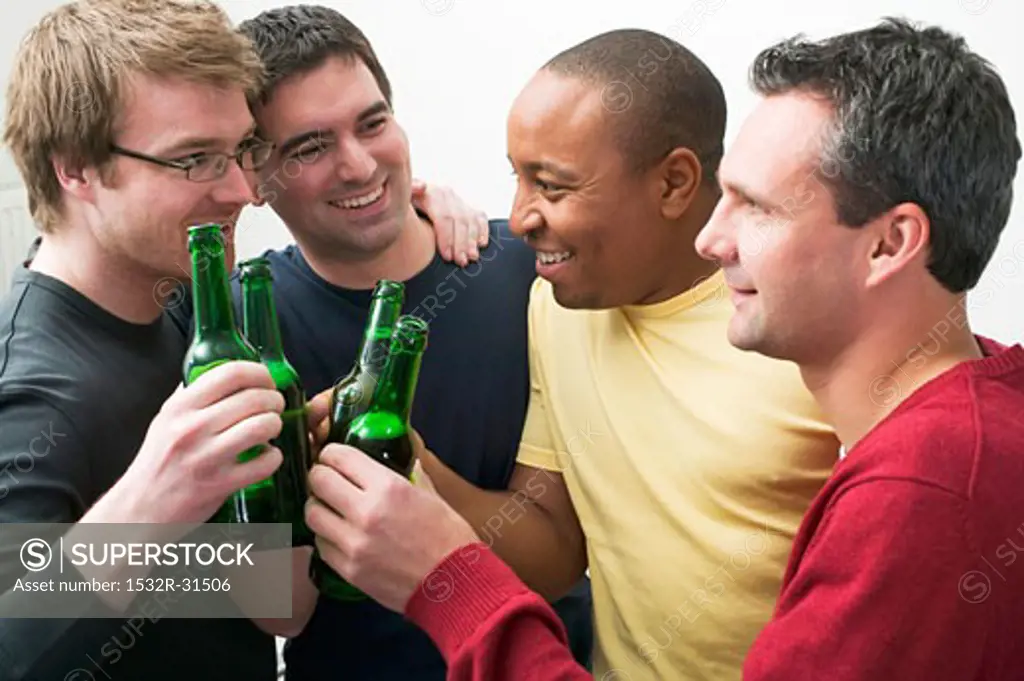 Four men clinking bottles of beer