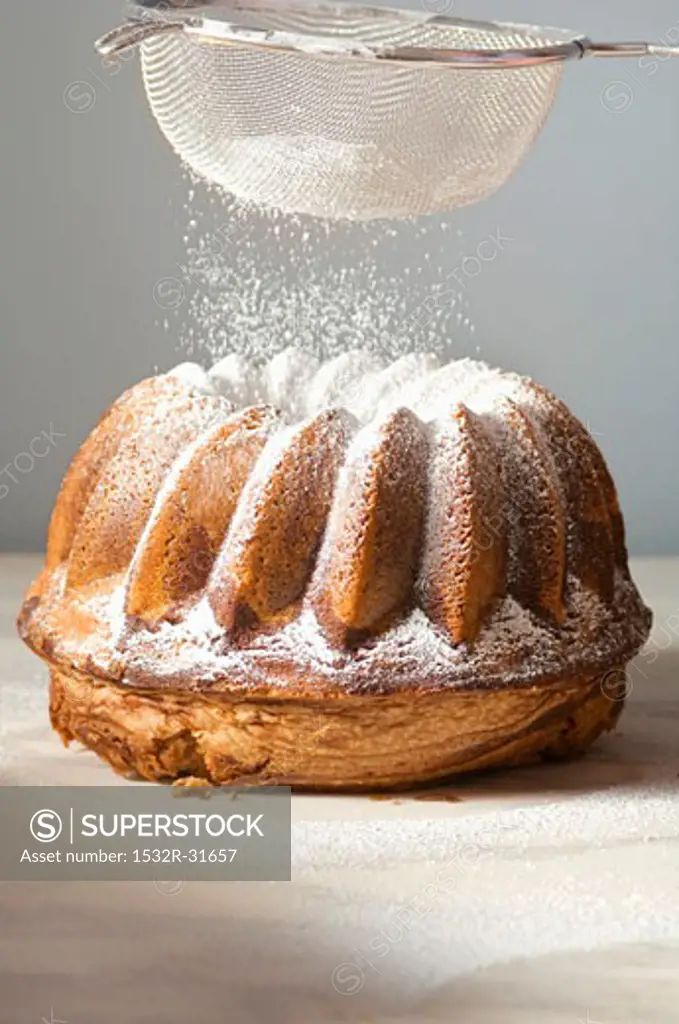 Sprinkling a marbled gugelhupf with icing sugar