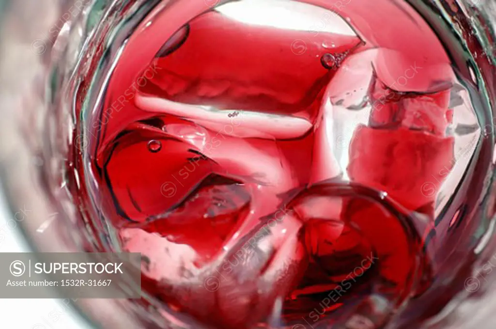 A glass of red fruit juice with ice cubes