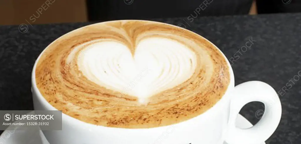 A cup of cappuccino with milk foam decorated with heart