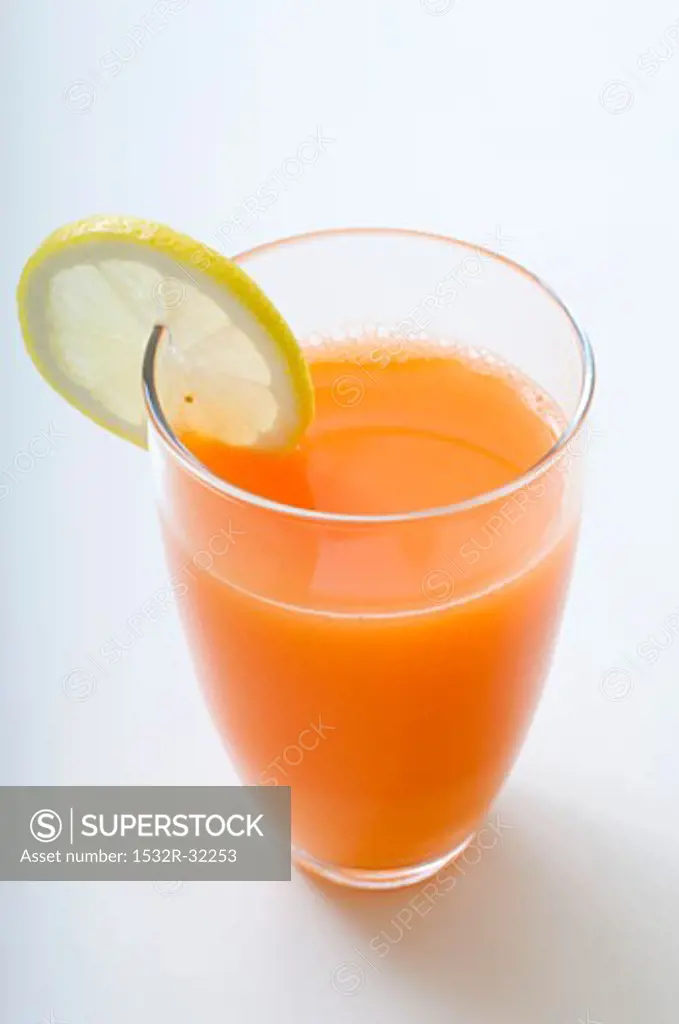 A glass of carrot juice with a slice of lemon