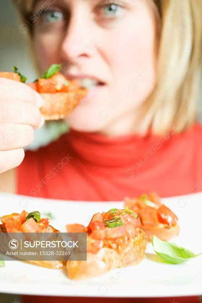 Woman eating bruschetta with fresh basil