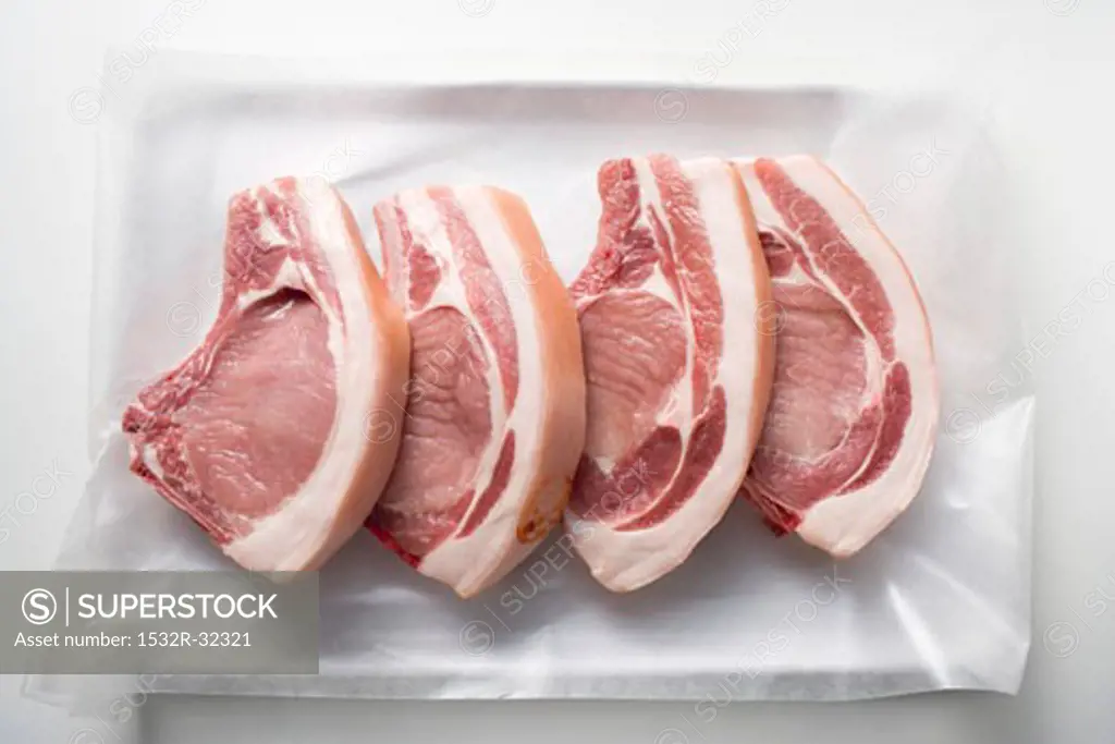 Four raw pork chops on paper