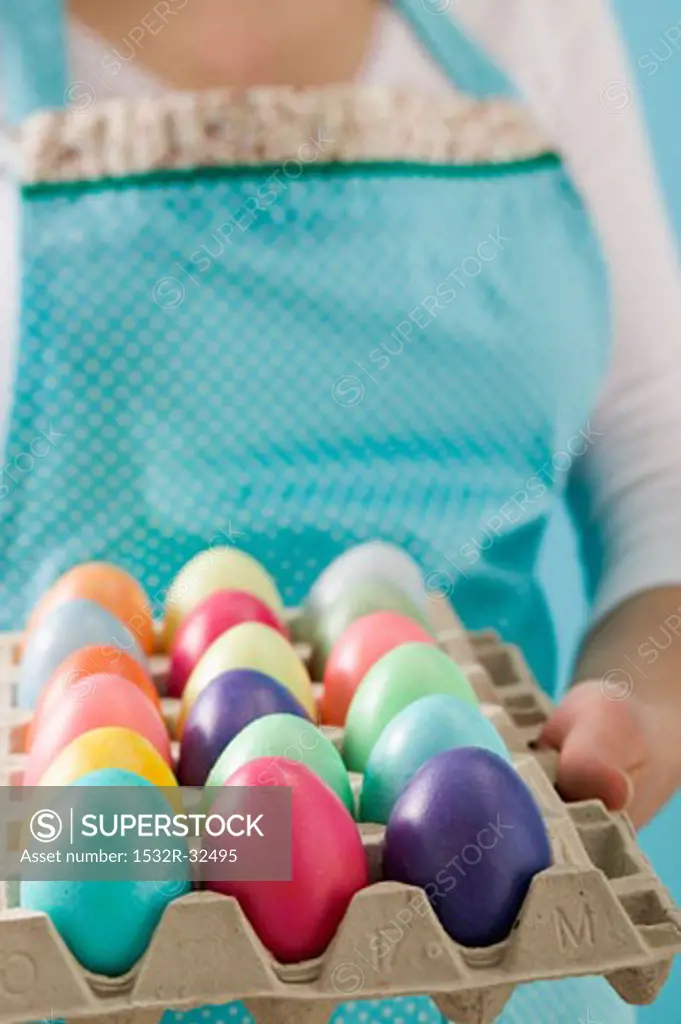 Woman holding egg tray full of coloured Easter eggs