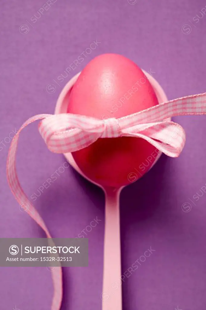 Red Easter egg with bow on spoon (overhead view)