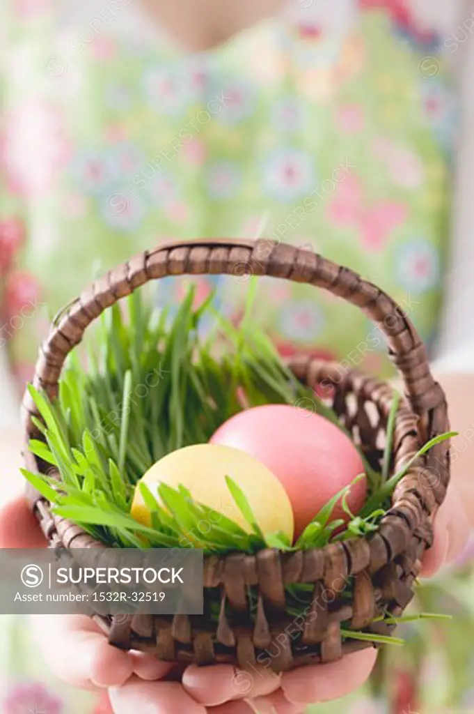 Woman holding basket of coloured Easter eggs