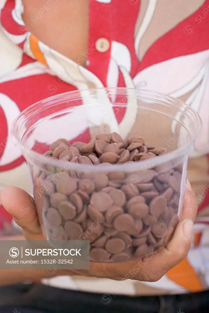 Person holding tub of chocolate buttons