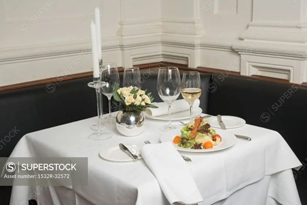Salad and white wine on laid table in restaurant
