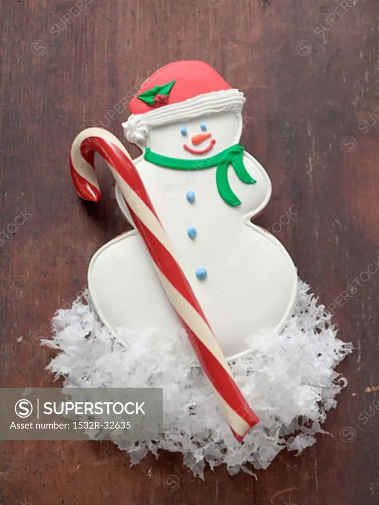 Snowman biscuit and candy cane on wooden background