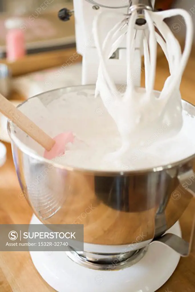 Whipped cream in the mixing bowl of a food mixer