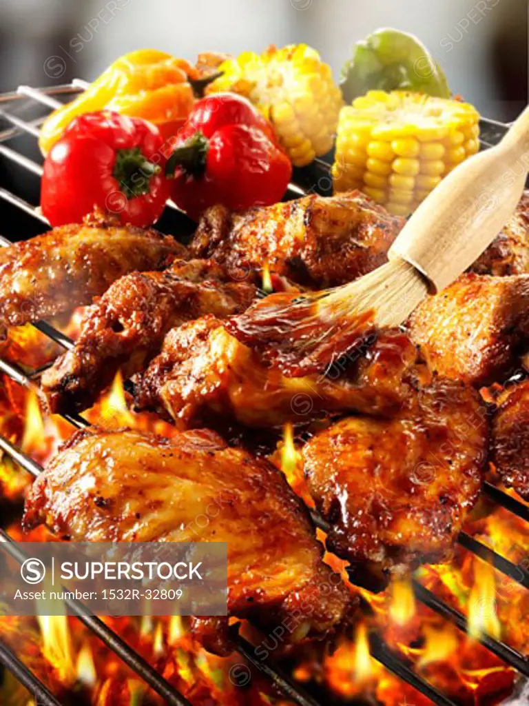 Brushing chicken wings on barbecue rack with marinade