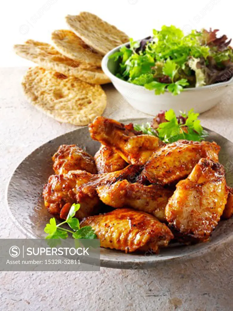 Grilled chicken wings with salad leaves and bread