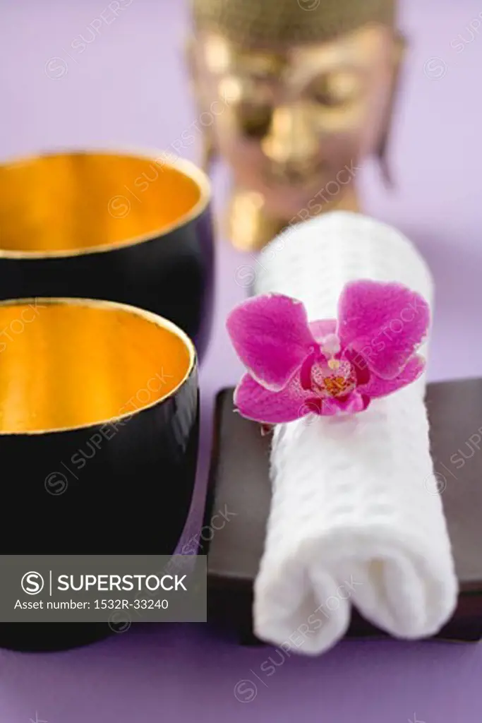 Two bowls, towel with orchid, statue of Buddha