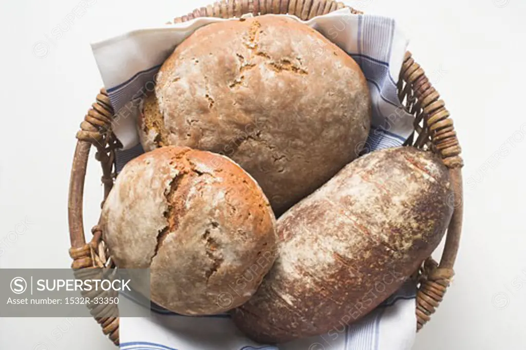 Three rustic loaves of bread in a bread basket