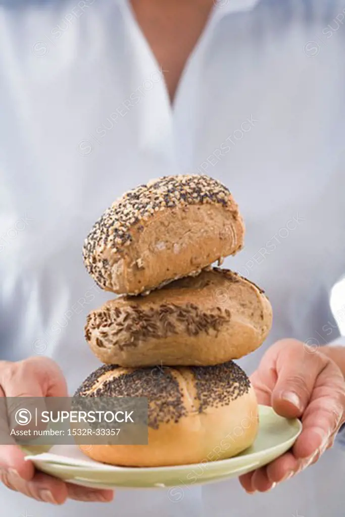 Woman holding three bread rolls on a plate