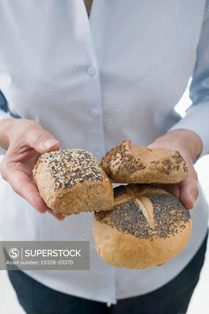 Woman holding three wholesome bread rolls